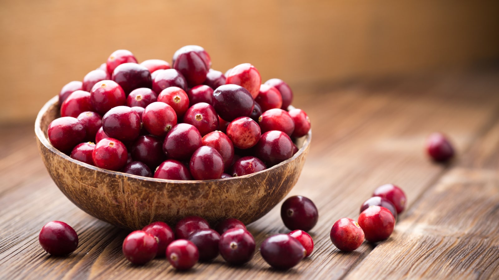 Cranberries in wooden bowl on wooden background.