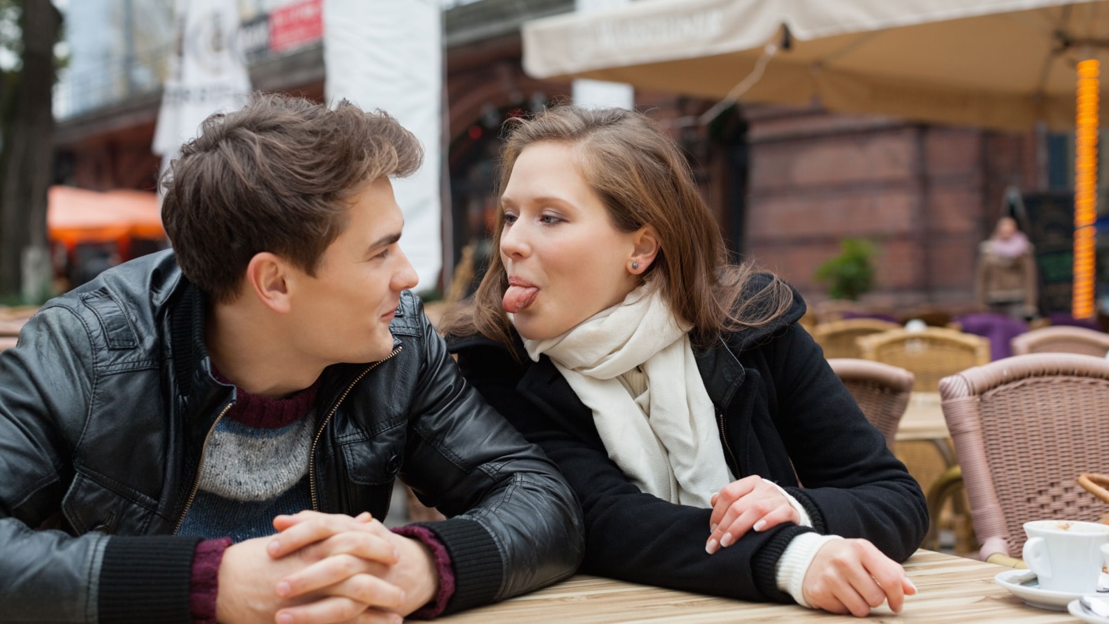 Young woman teasing man while sitting at outdoor restaurant