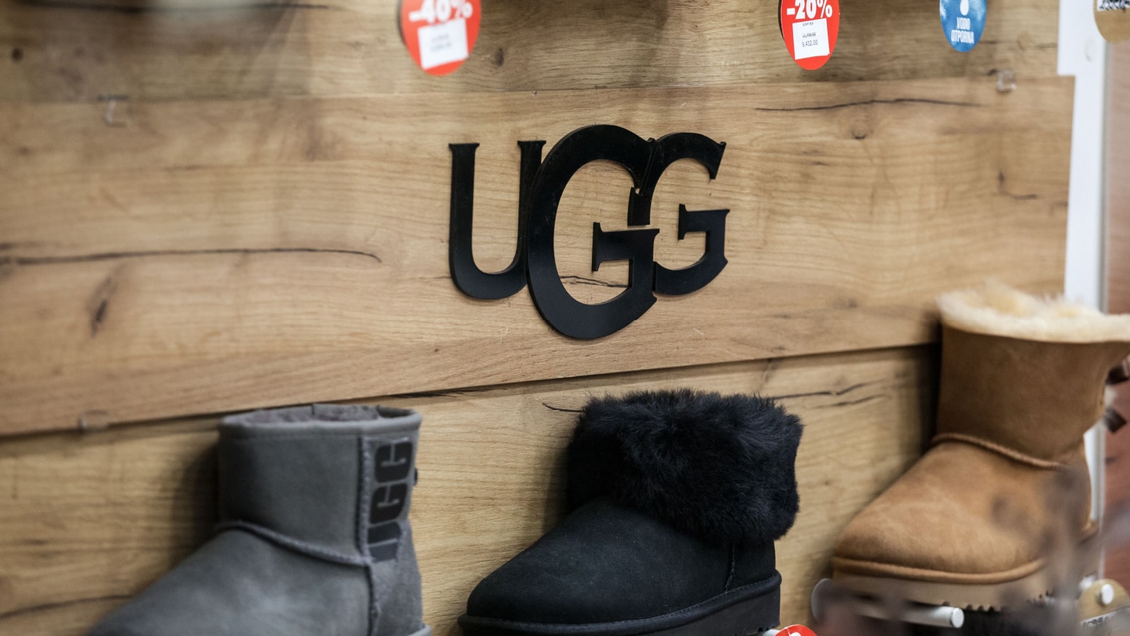 BELGRADE, SERBIA - DECEMBER 8 2020: Ugg logo in front of some of their boots for sale in a shop. Ugg is an american footwear brand known for their sheepsking boots.