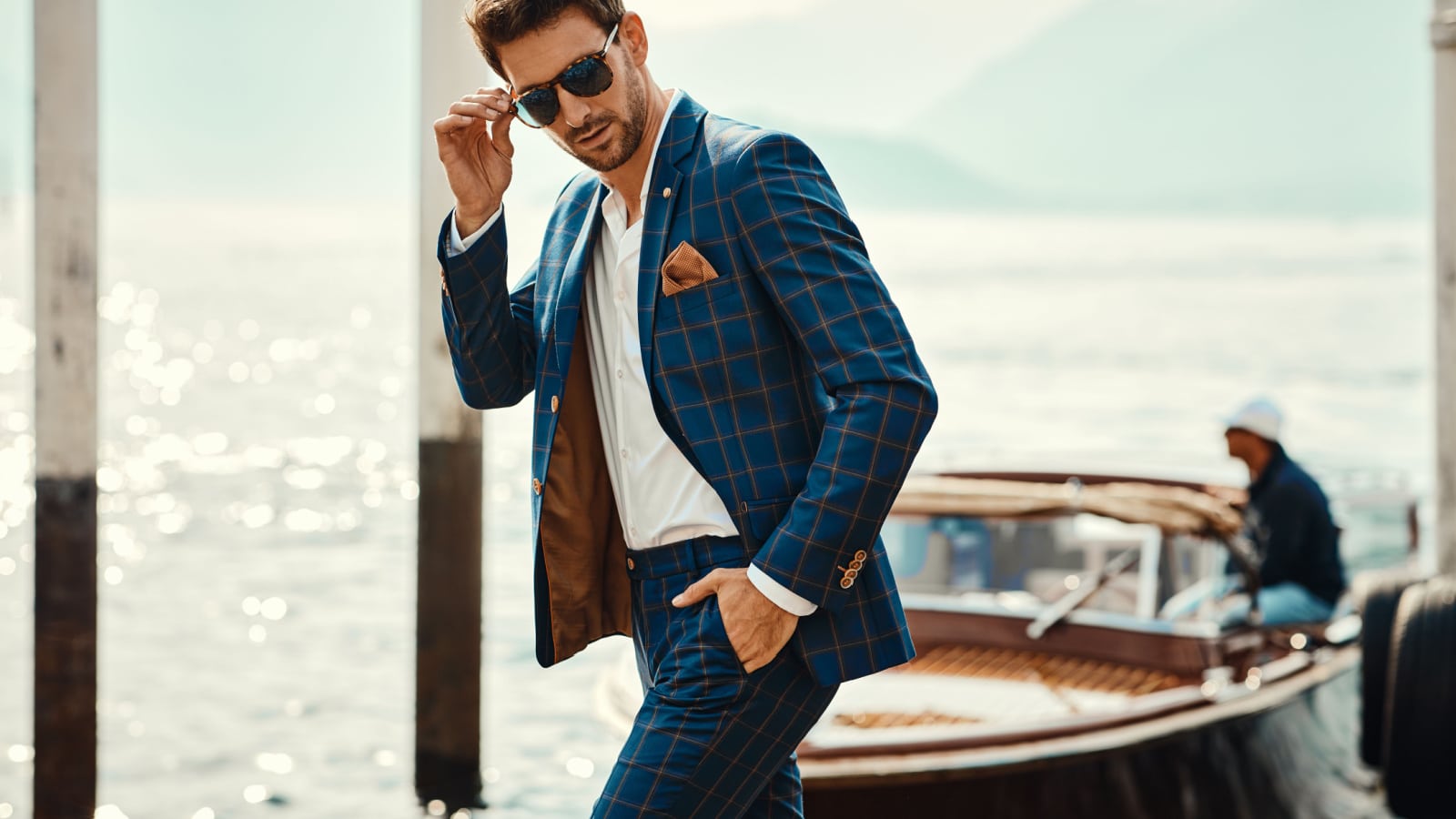 Young handsome man in classic suit wear sunglasses over the blurred lake