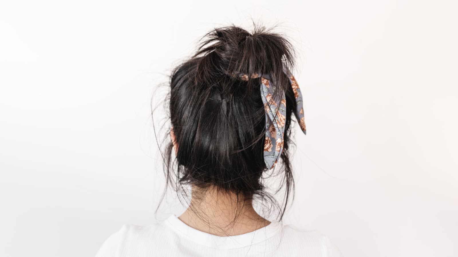 Messy damaged long black hair, on white background in a hair bun