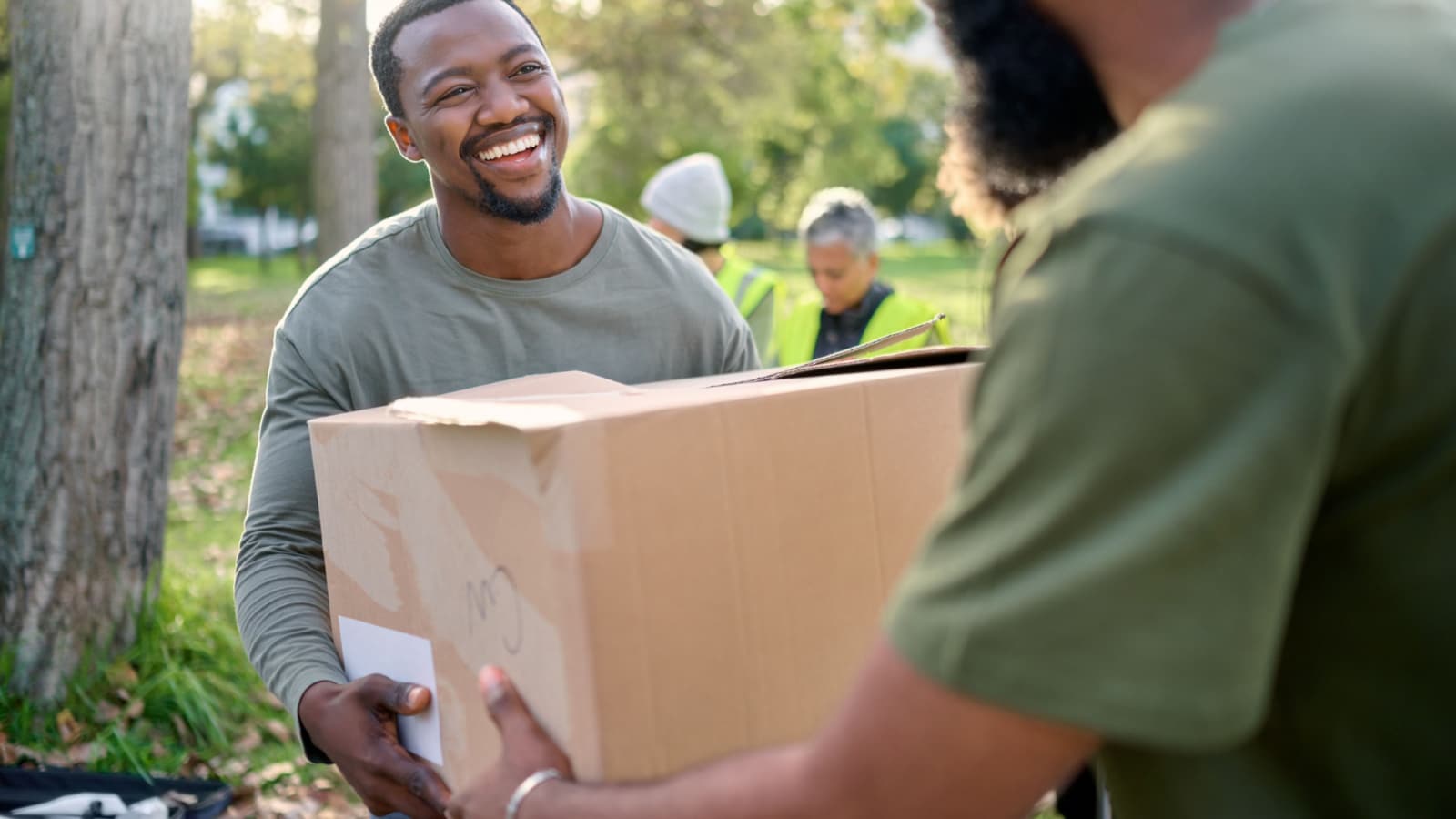 Black man, volunteering and giving box in park of donation, community service or social responsibility. Happy guy, NGO worker and helping with package outdoor for charity, support or society outreach