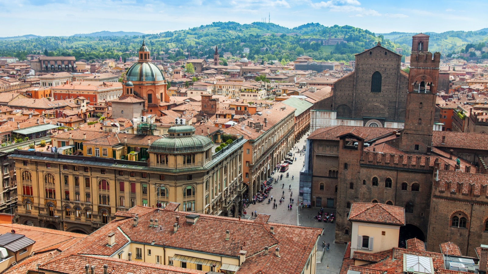 An aerial view of the old city of Bologna, Italy, where people walk the streets lined with ancient buildings.