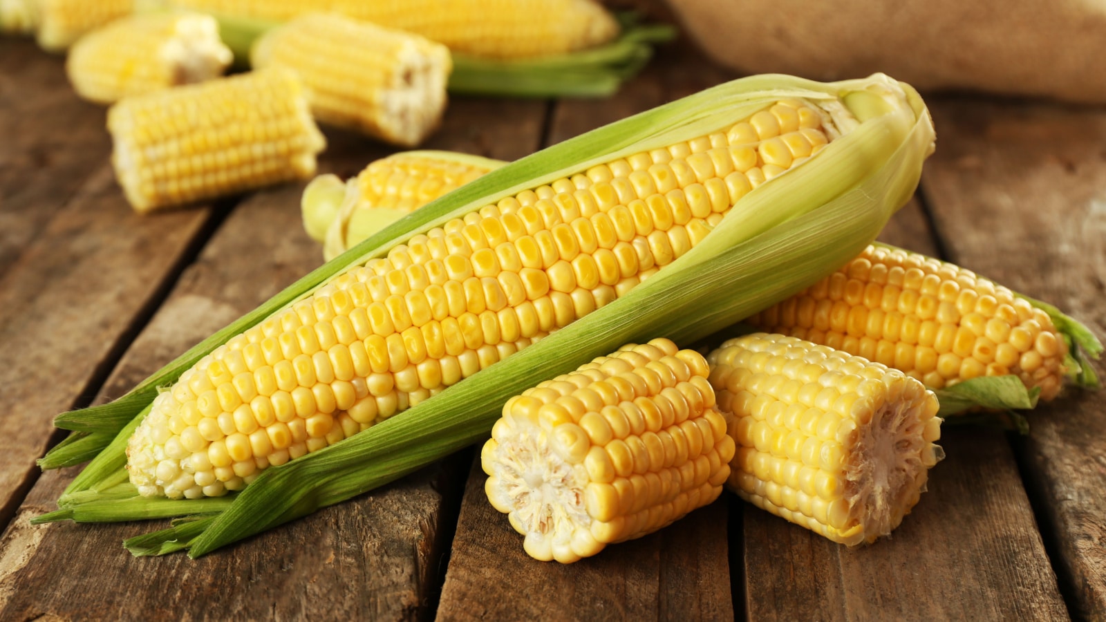 Fresh corn on cobs on rustic wooden table, closeup