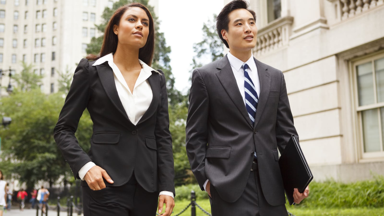 Two well dressed professionals walking down a city street. Could be lawyers, business people etc.