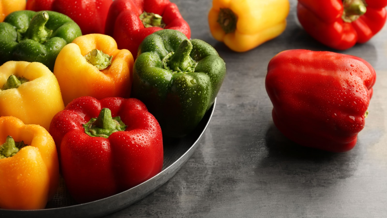 Red, green and yellow sweet bell peppers on table, close up