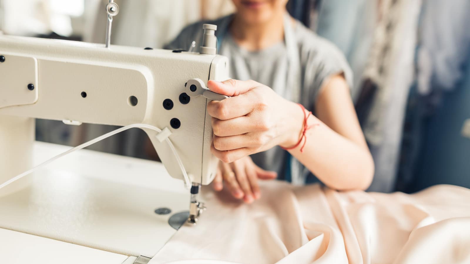 loseup portrait of young woman seamstress sitting and sews on sewing machine. Dressmaker work on the sewing machine. Tailor making a garment in her workplace. Hobby sewing as a small business concept