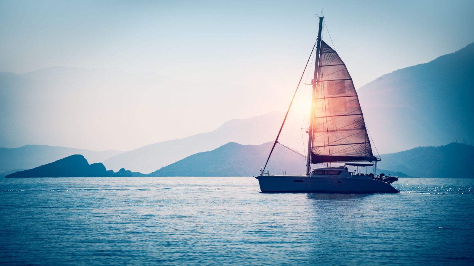 Sailboat in the sea in the evening sunlight over beautiful big mountains background, luxury summer adventure, active vacation in Mediterranean sea, Turkey