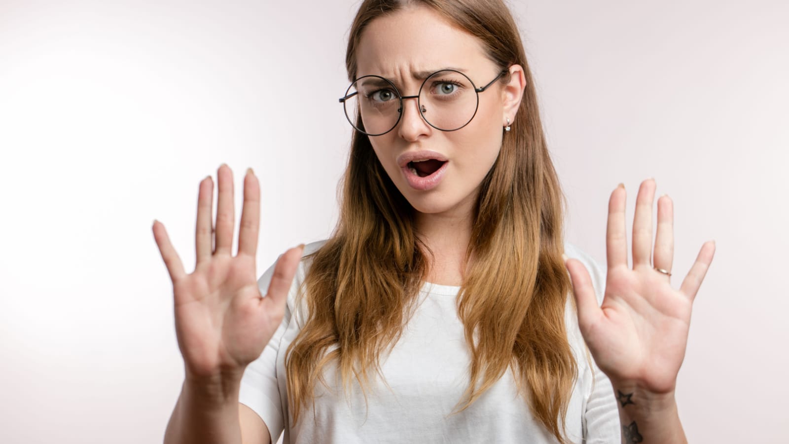 Young beautiful woman in glasses making the hand stop sign, isolated on the white background. close up photo. calm down, please. Don't worry