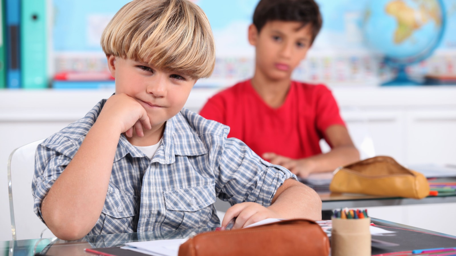 schoolboys seated at desk in classroom with bowl haircut