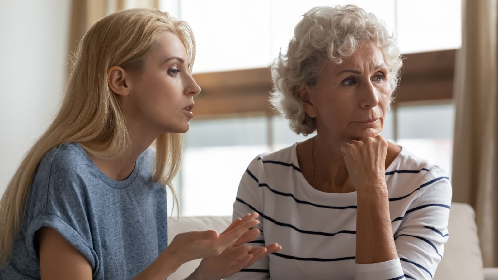 Irritated young woman asserting opinion to offended middle aged mother at home. Annoyed blonde grown up daughter arguing with stubborn mature elderly mom, two generations family disagreements concept.