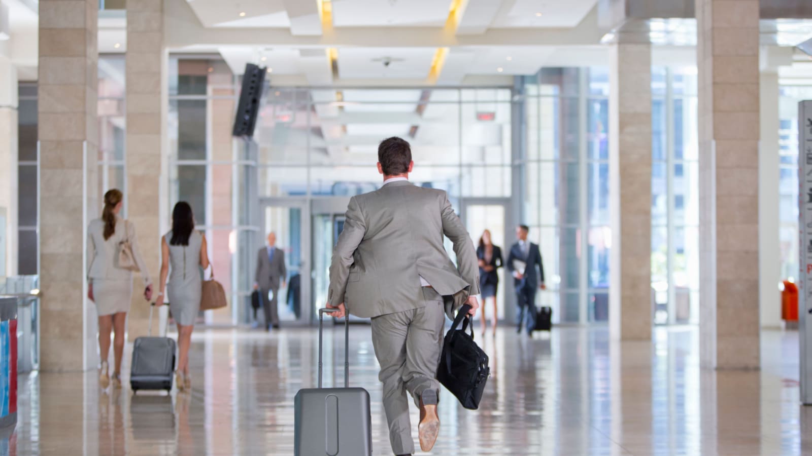Portrait of a businessman running at an airport carrying a travel suitcase and a briefcase