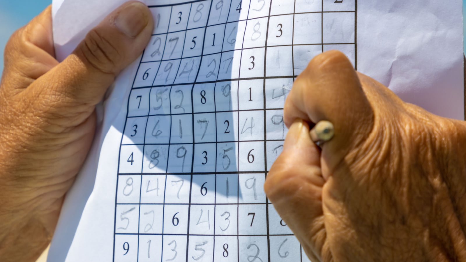 Senior person playing sudoku number puzzle outside