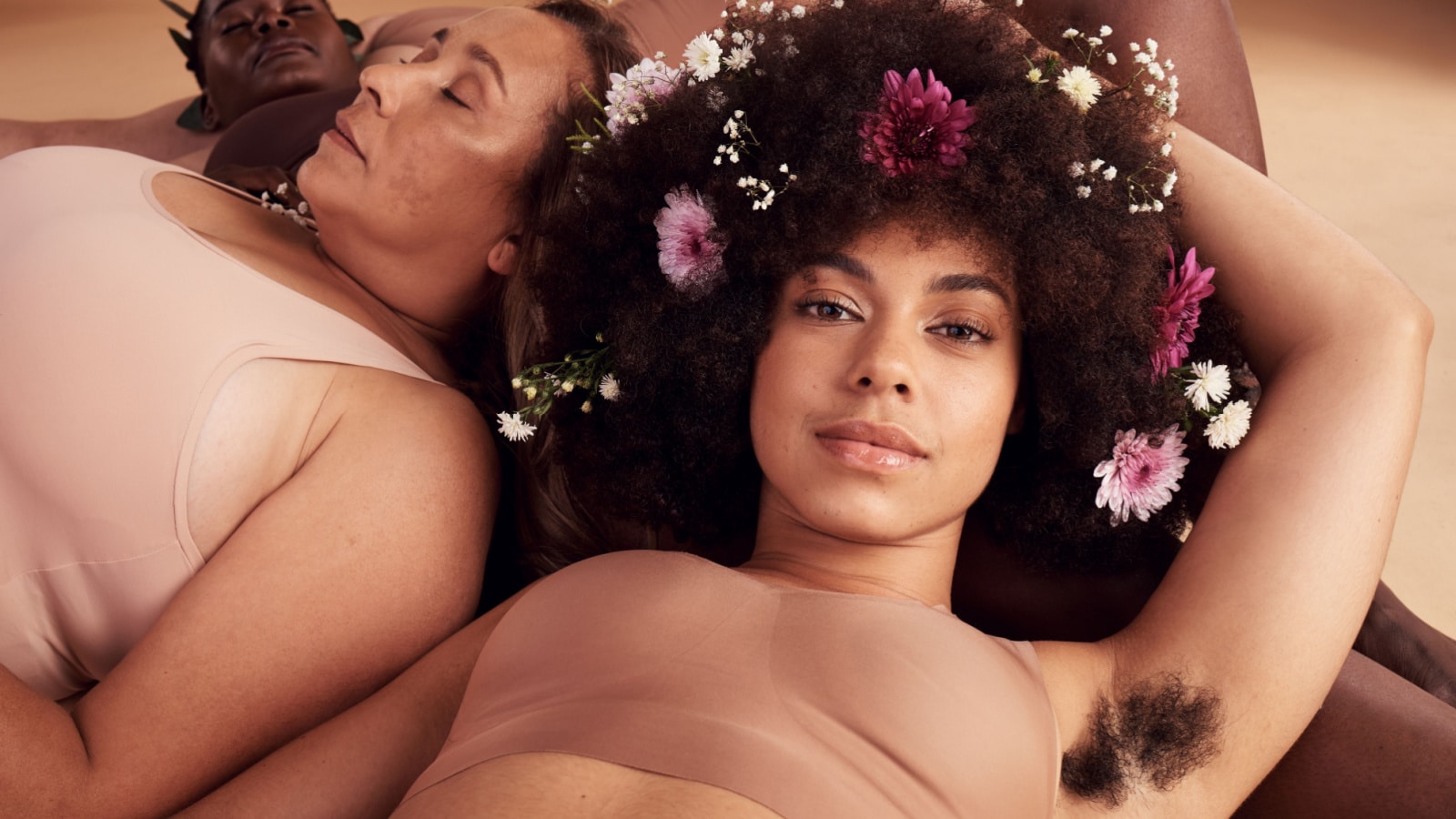 Armpit hair, confidence and floral black woman with natural beauty, body health and happy in skin with a group of women in studio. Creative, flower crown and portrait of a model with hairy underarm