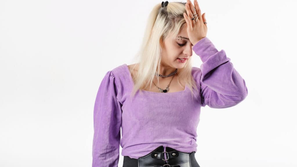 Young beautiful woman wearing lilac ribbed blouse isolated over white background making facepalm gesture with hand. Face palm concept.