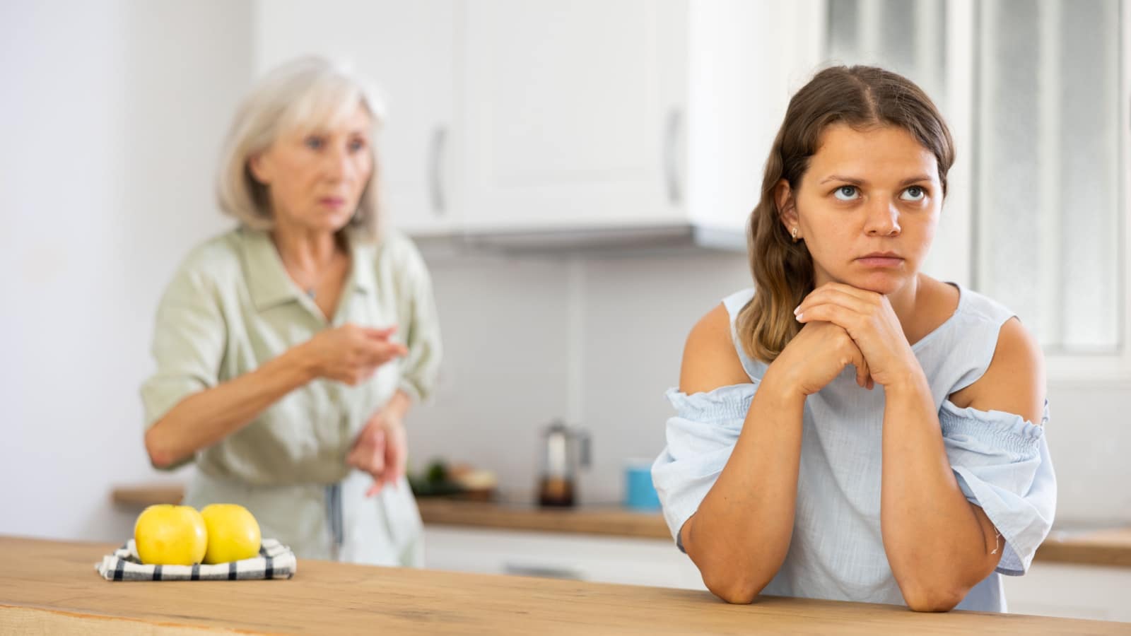 Aggrieved woman having quarrel with her elderly mother in kithcen at home