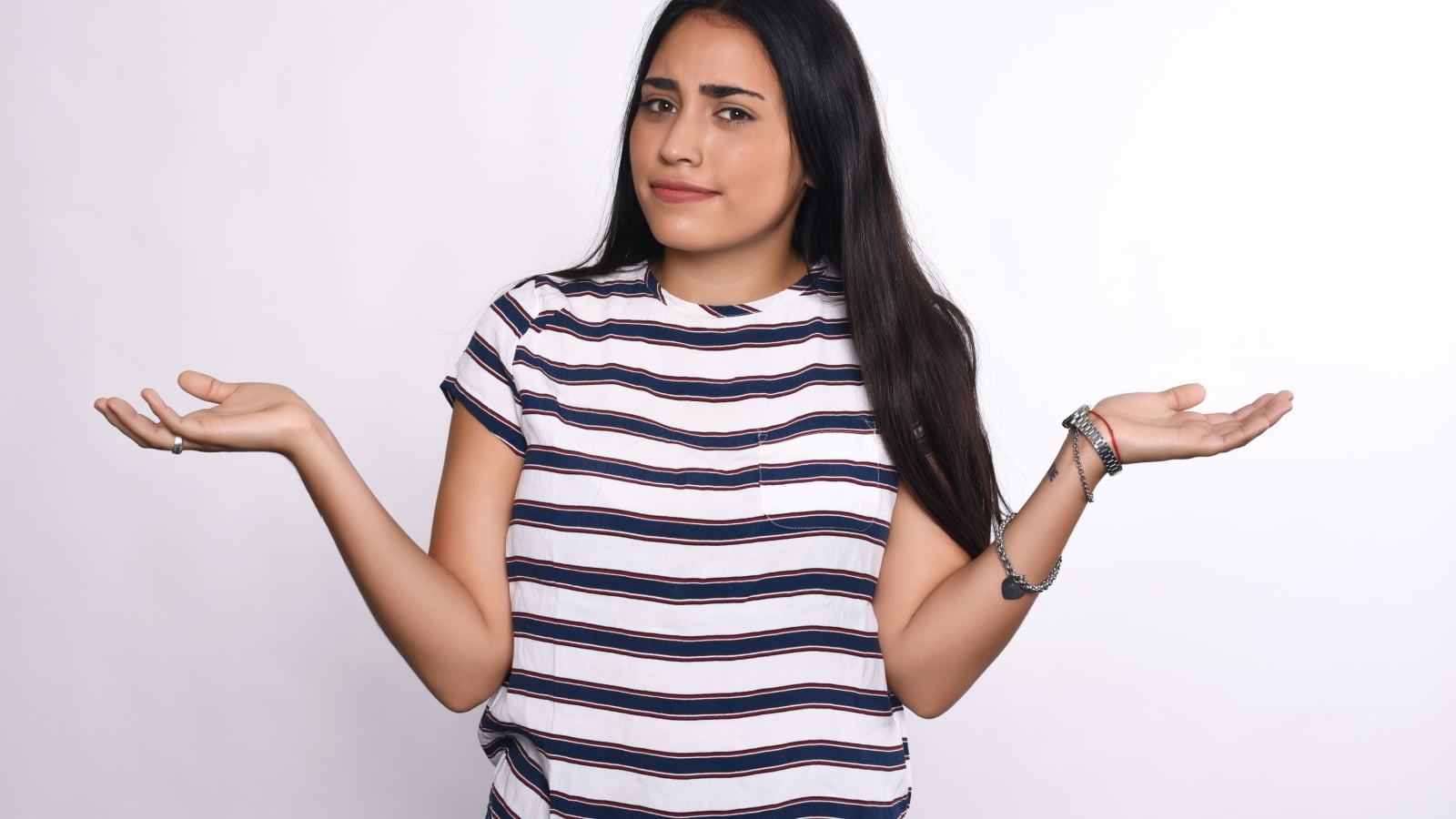 Indecisive young woman with arms open. Isolated white background.