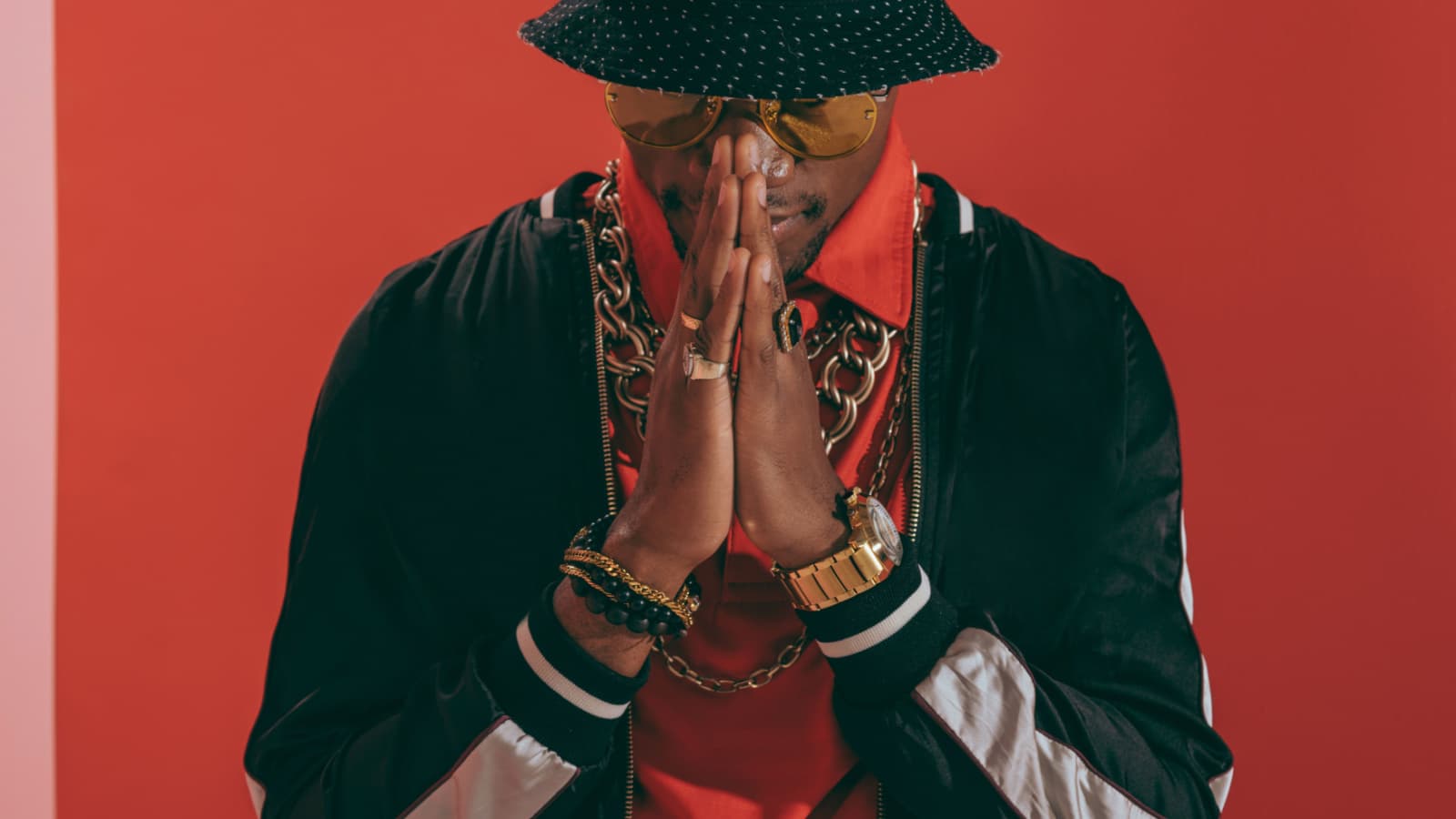 portrait of stylish african american man wearing jewellery and hat standing in studio