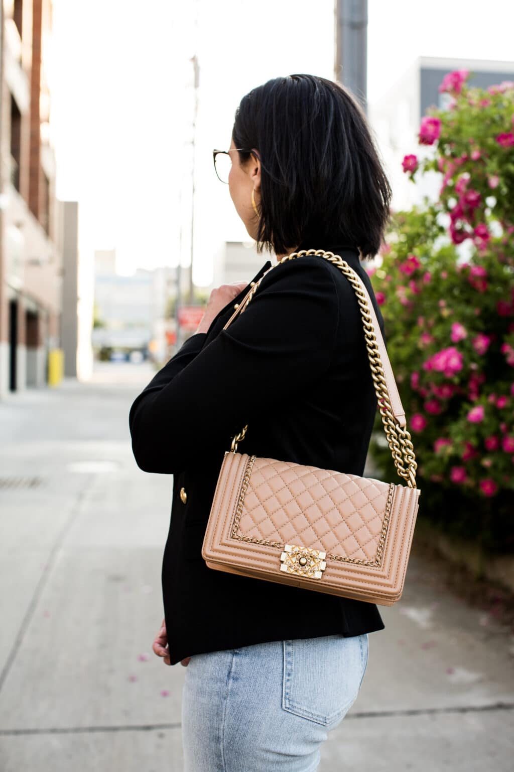 Lindsey of Have Clothes, Will Travel showing a pink Chanel boy bag paired with a black blazer and jeans