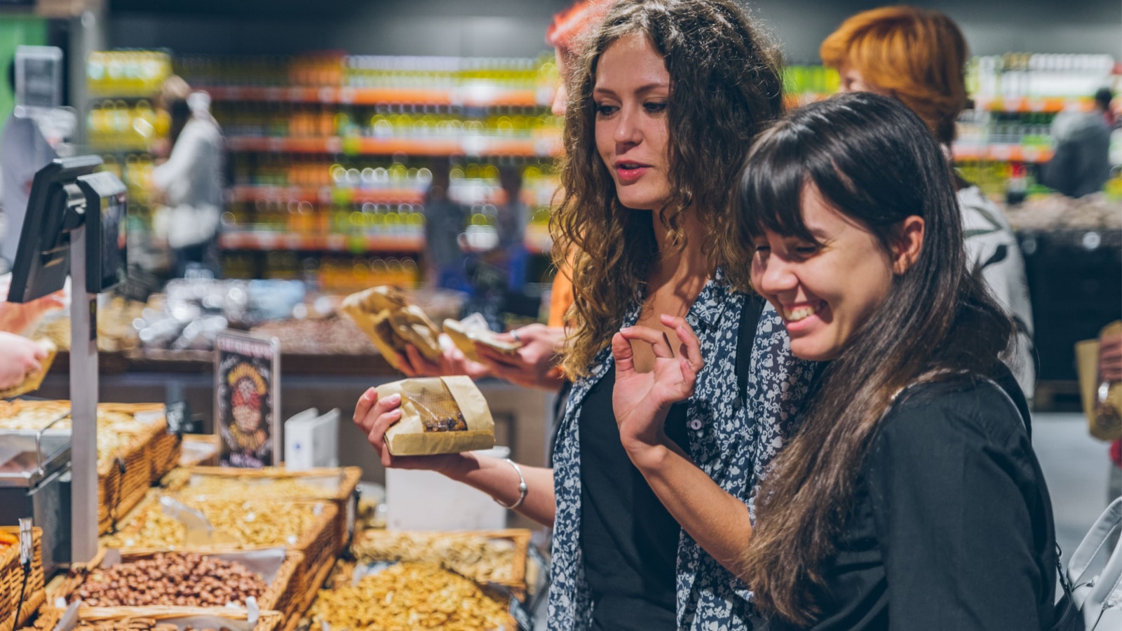 two women buying dried fruit in grocery store. lifestyle
