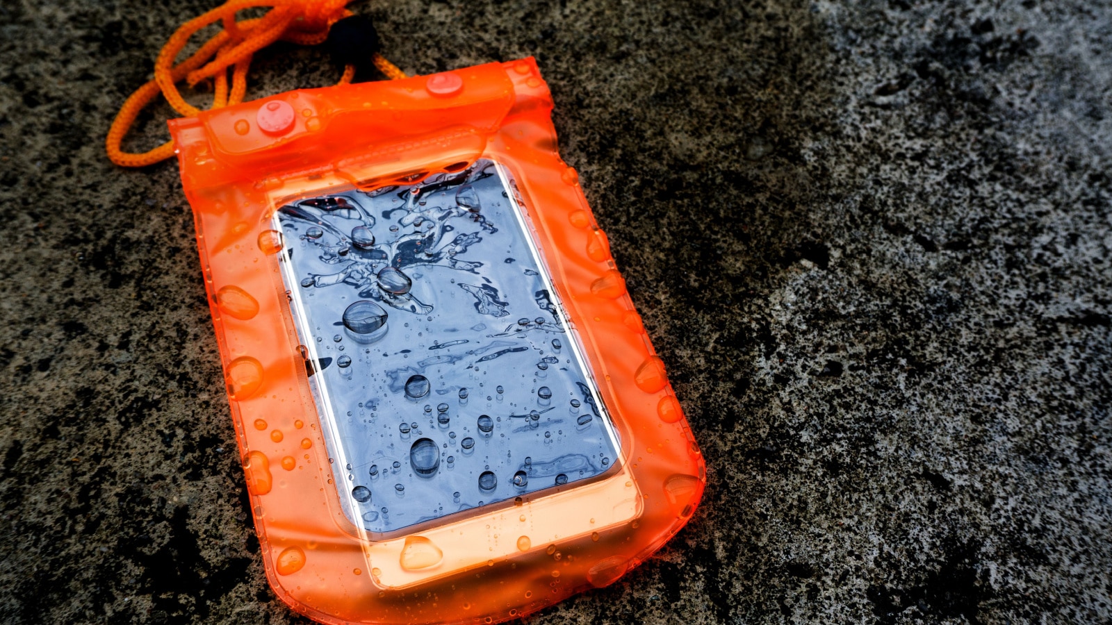 Orange waterproof mobile phone case with water droplets on grunge texture background.PVC zip lock bag protect mobile phone or important items from water.Concept for Songkran water festival in Thailand