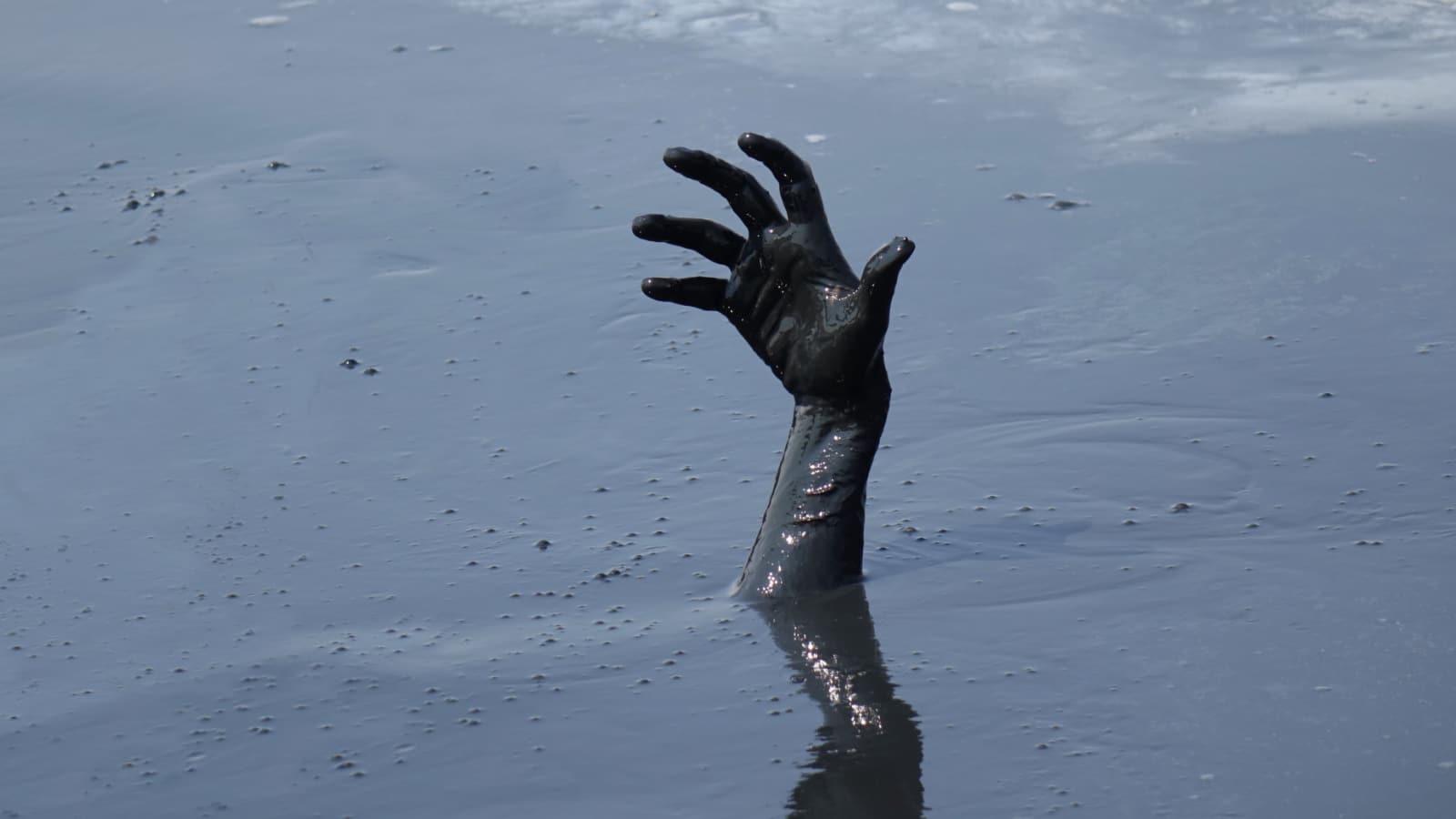 hand of a man drowning in mud