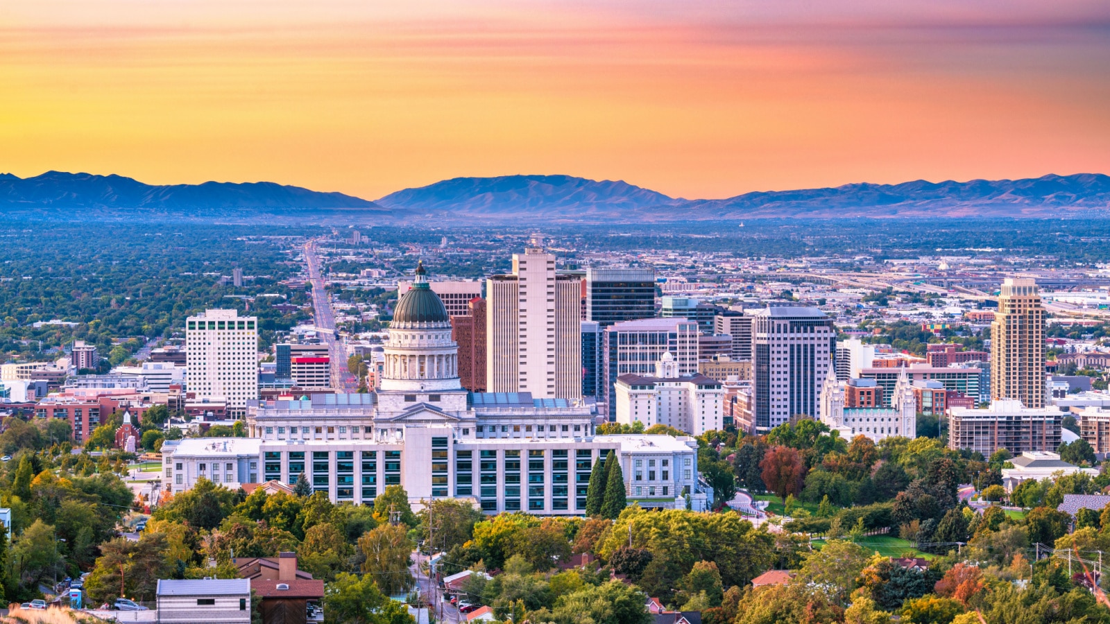 An aerial photo of downtown Salt Lake City, Utah, at dusk, showing the city skyline with mountains in the background.