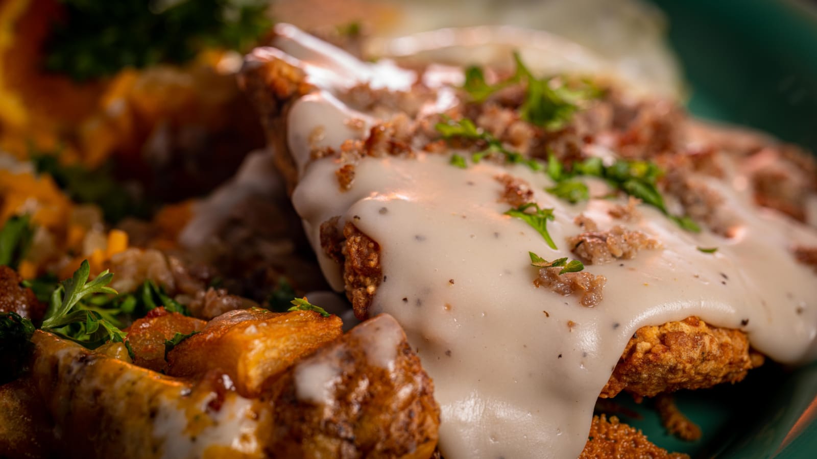 A crispy chicken fried steak with cheesy potatoes, eggs and gravy.