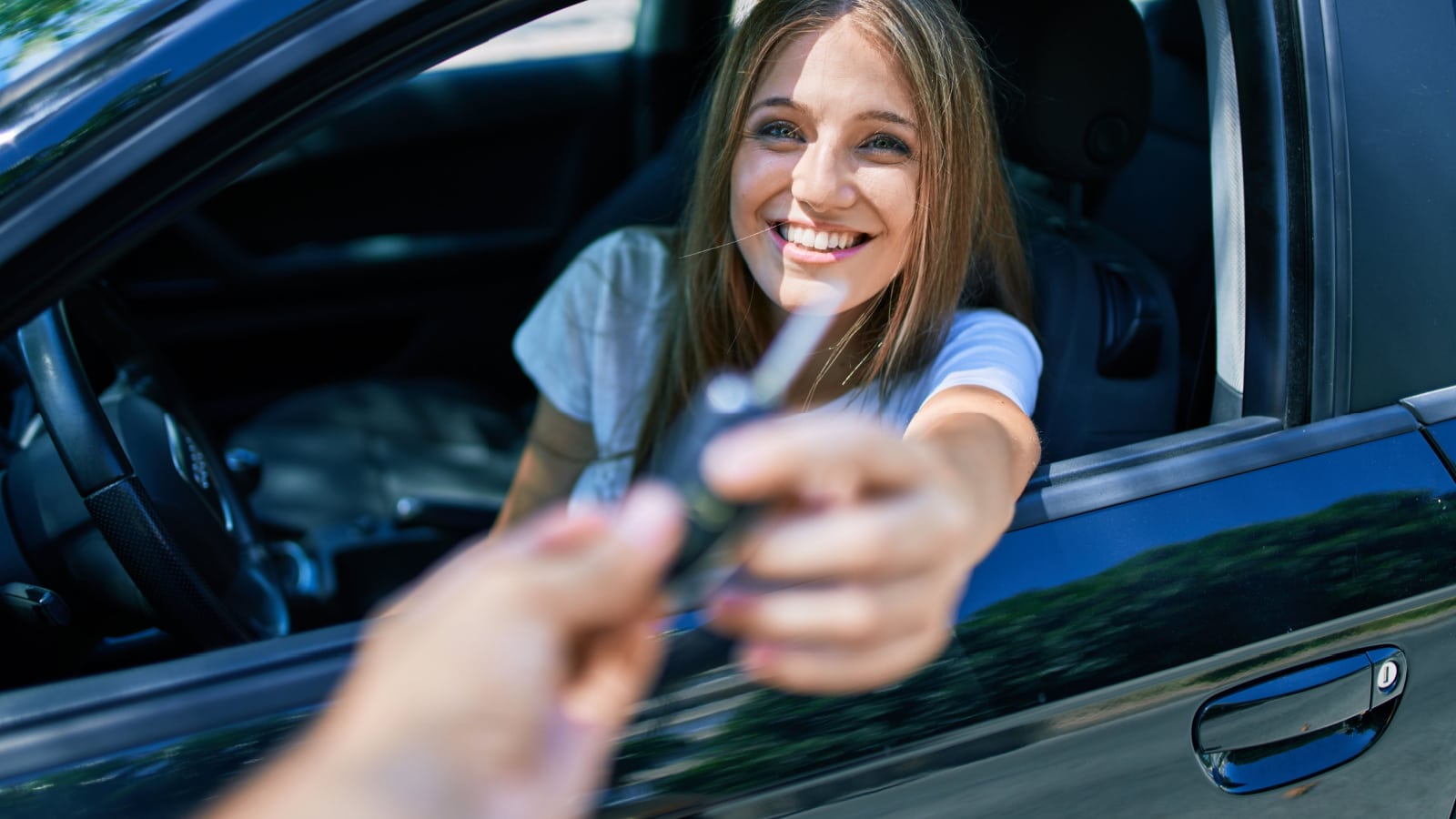 Young beautiful blonde woman smiling happy holding key of a new car.
