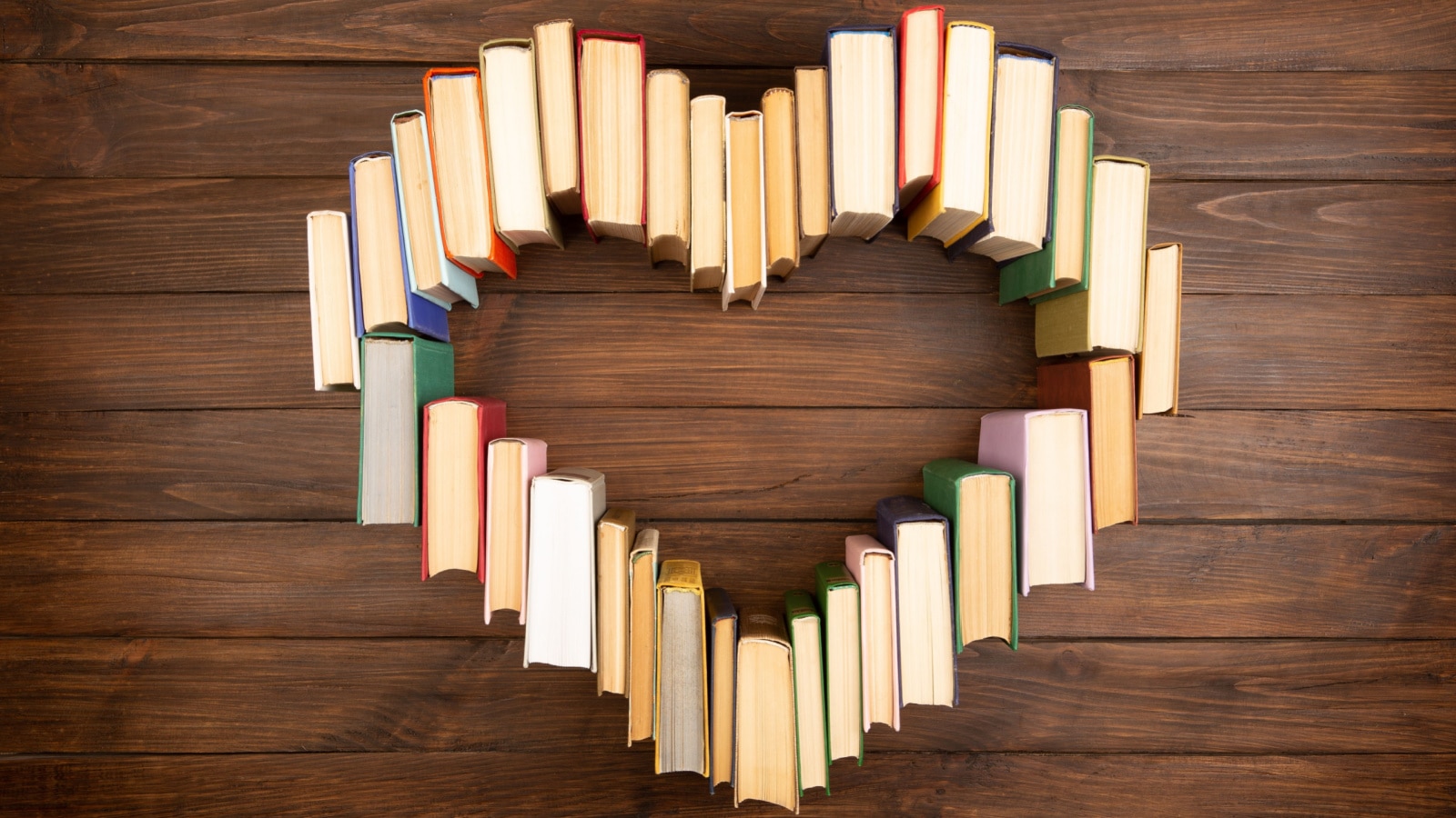 Love of books reading. Stack of books in the colored cover lay on the table in the shape of a heart. Library, education. Empty space for Your text.