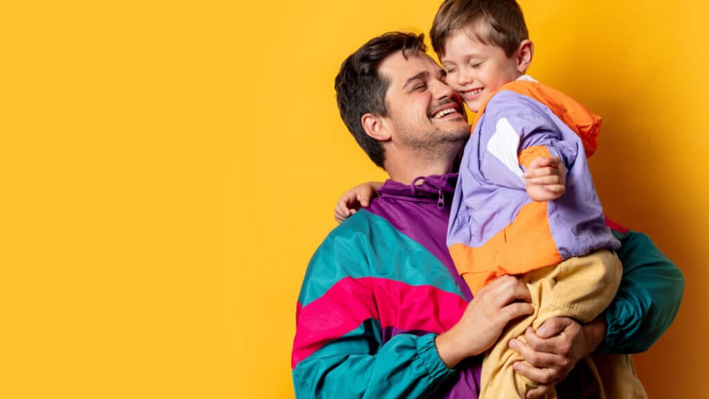 Father with son in 80s vintage sport suits on yellow background