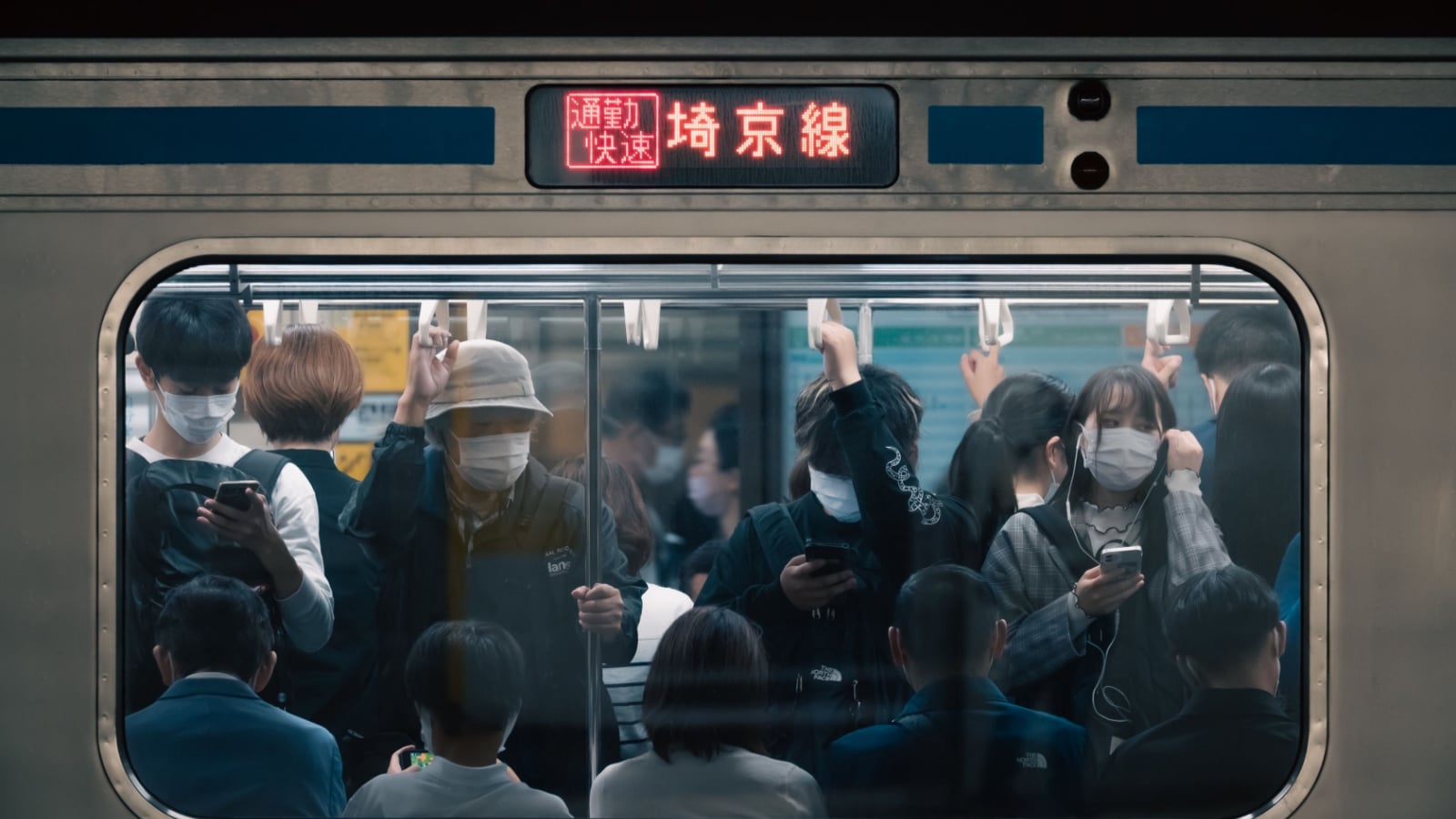 Tokyo, Japan - 10.2022: Japanese rush hour with worker and student commuting on express train crammed into the carriage