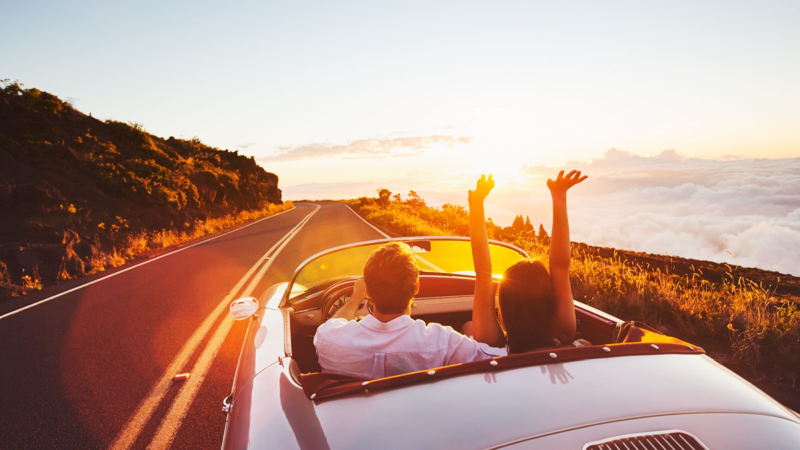 Happy Couple Driving on Country Road into the Sunset in Classic Vintage Sports Car