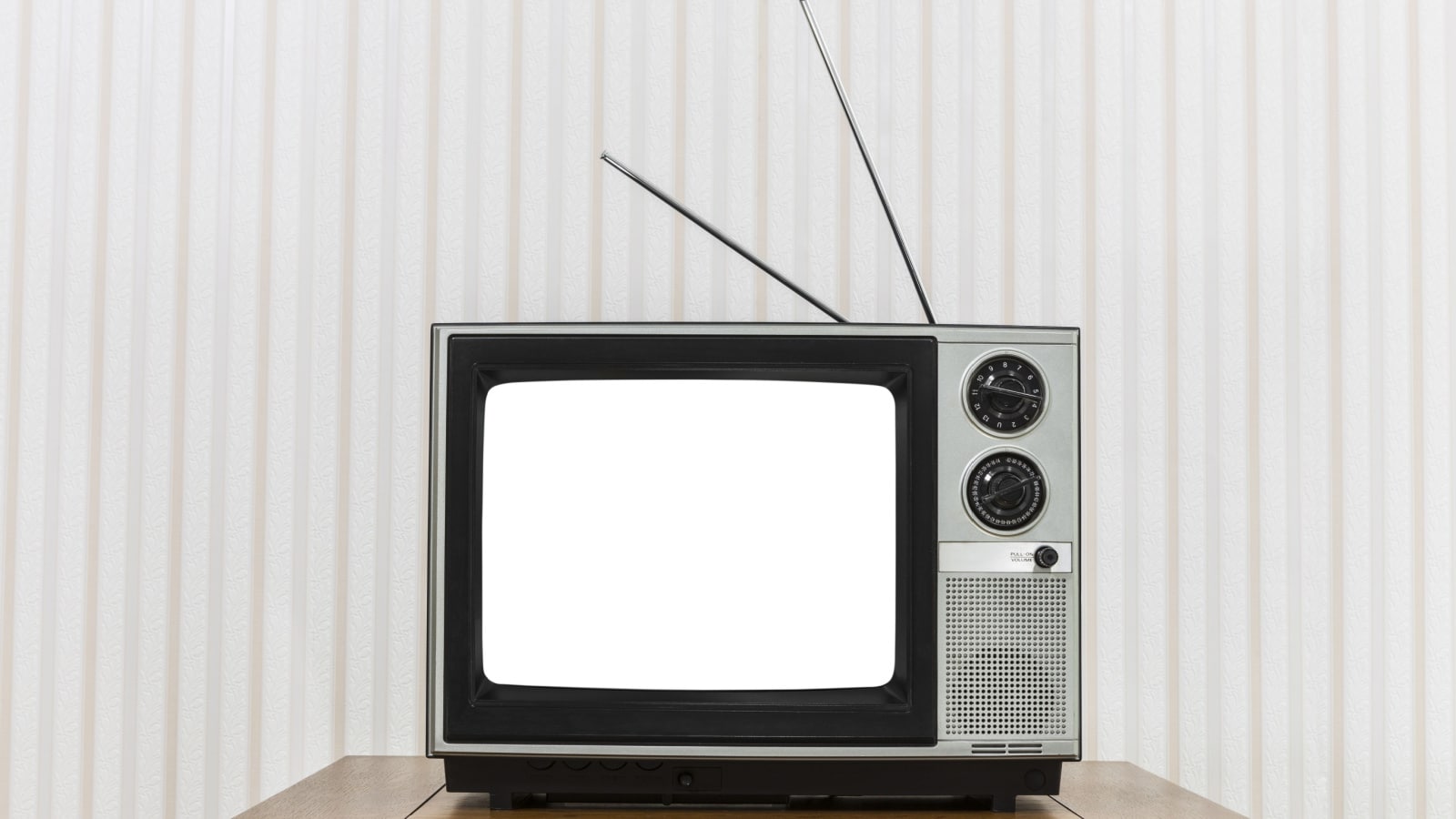 Old analogue television on wood table with white cut out screen.