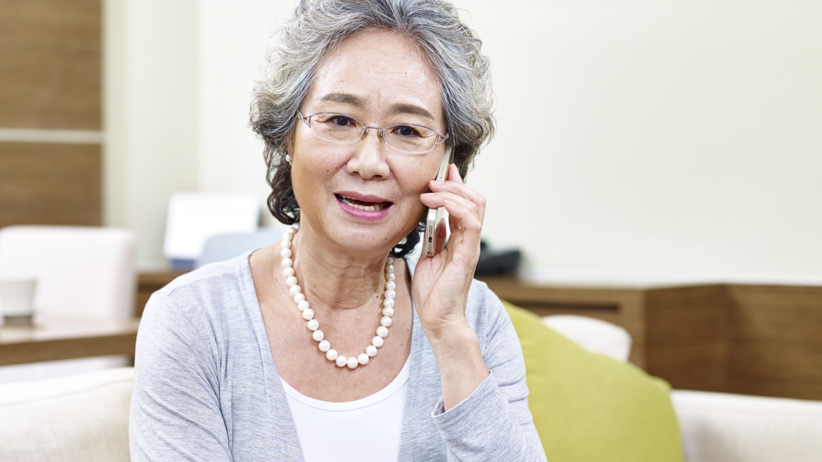 senior asian woman talking on cellphone, appears to be disappointed, upset and unhappy