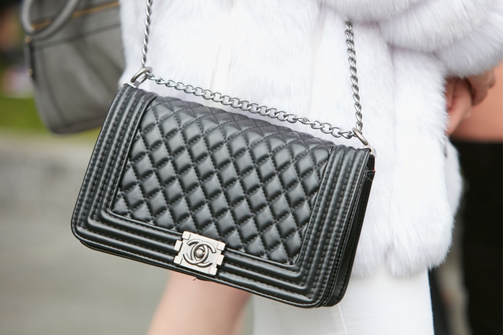 MILAN - FEBRUARY 24: Woman with black Chanel leather bag and white fur before Emporio Armani fashion show, Milan Fashion Week street style on February 24, 2017 in Milan.