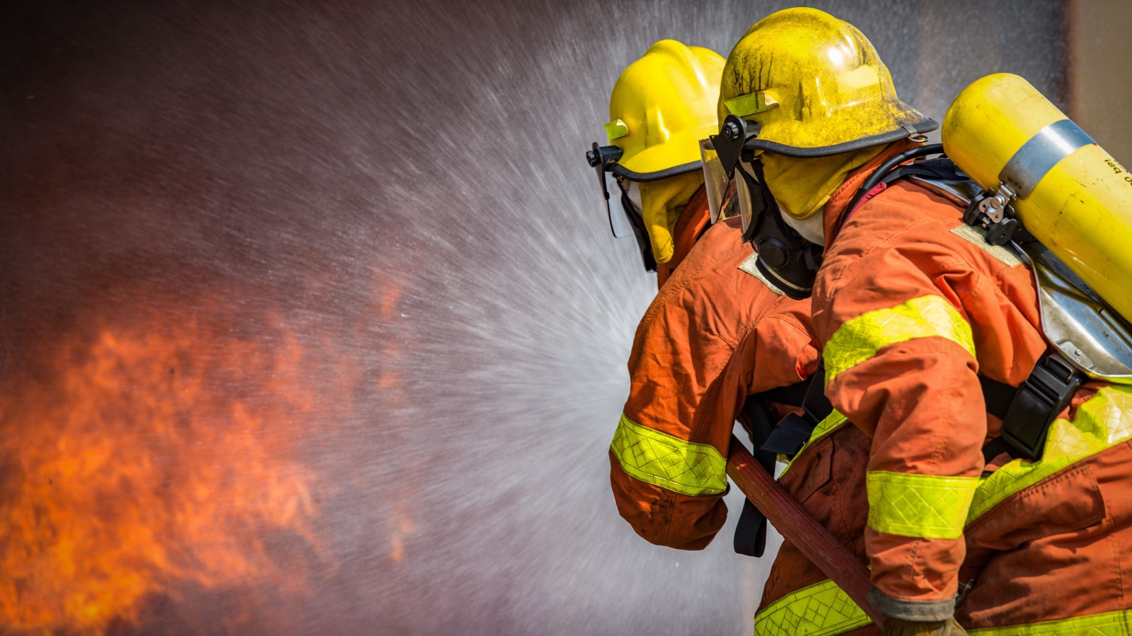 2 firefighters spraying high pressure water to fire with copy space