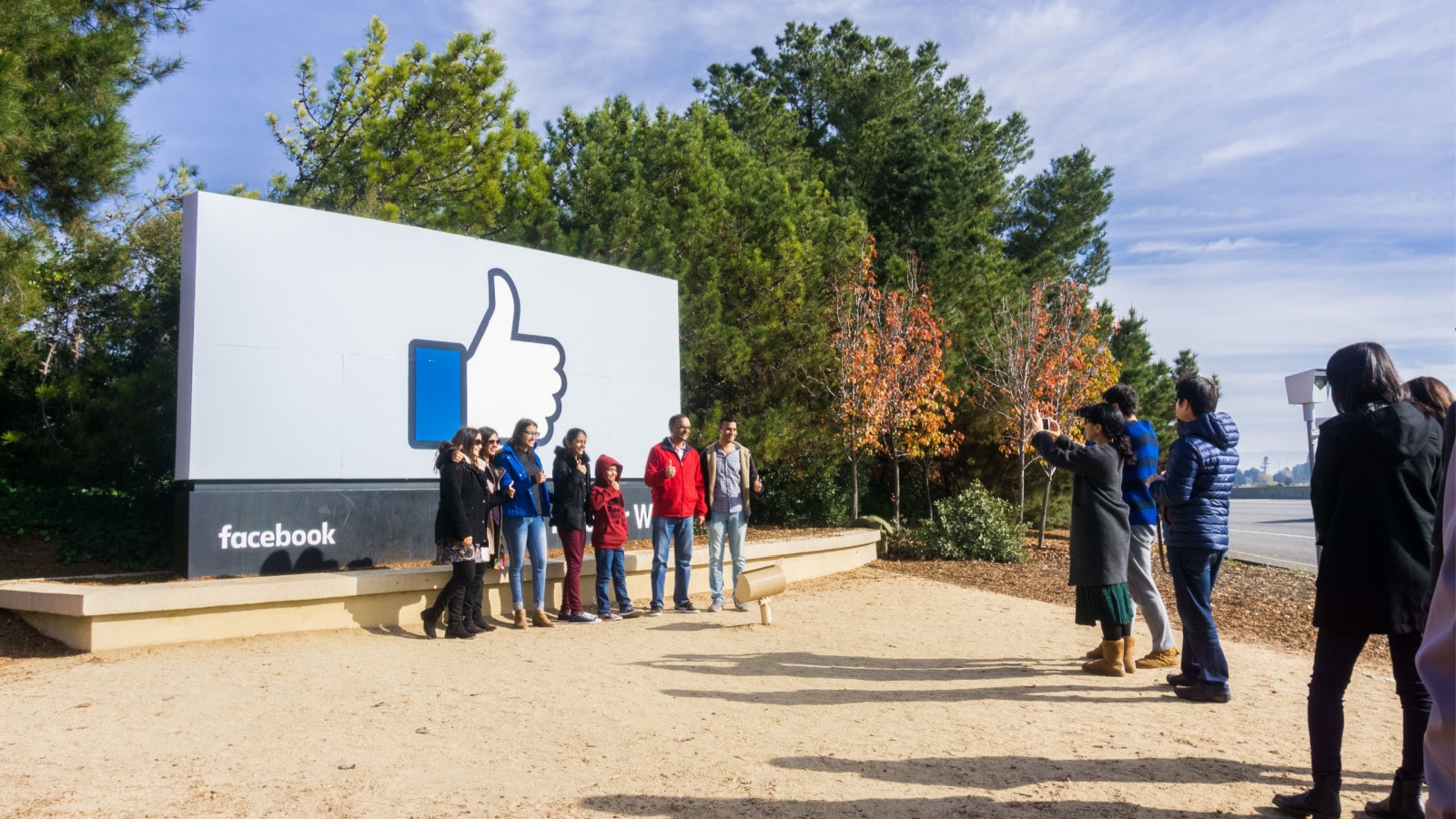 December 27, 2017 Menlo Park / CA / USA - A group of friends posing in front of the Facebook Like Button sign located at the entrance to the company's main headquarters located in Silicon Valley