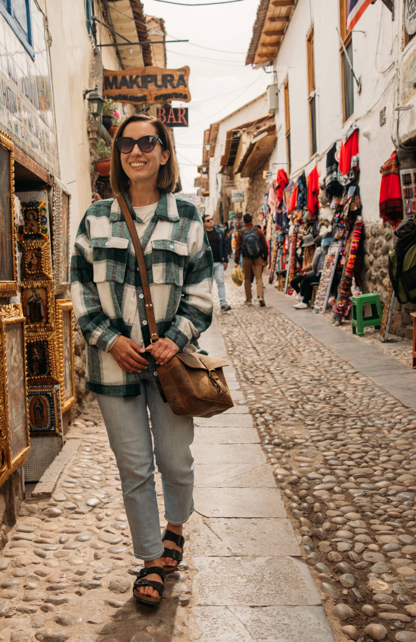 Lindsey of Have Clothes, Will Travel wearing Carve Designs jeans and a revolve flannel in Cusco, Peru