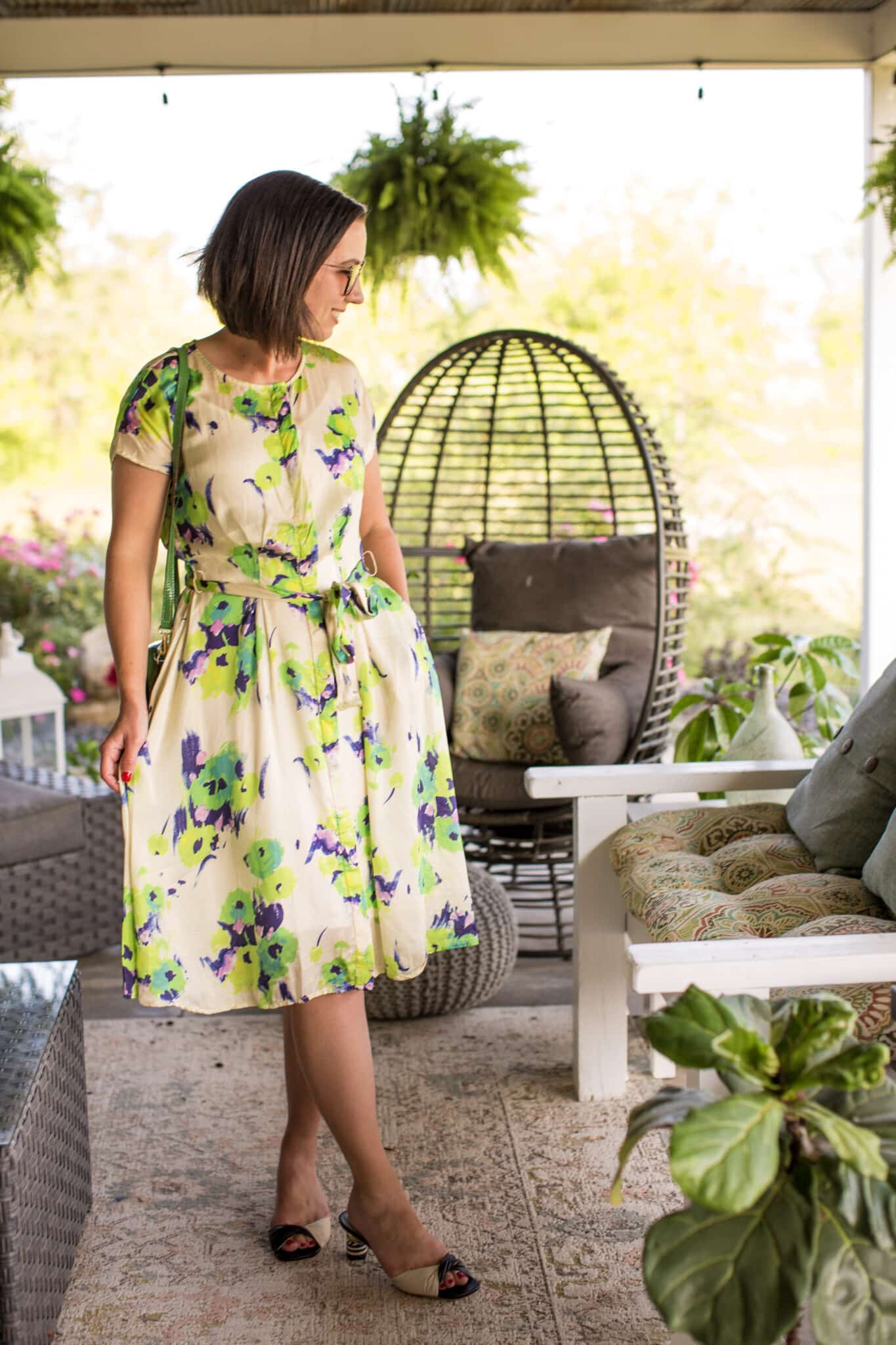 Lindsey wears the Anna Slope Arm Dress in Tuileries Oyster Green on a summer patio