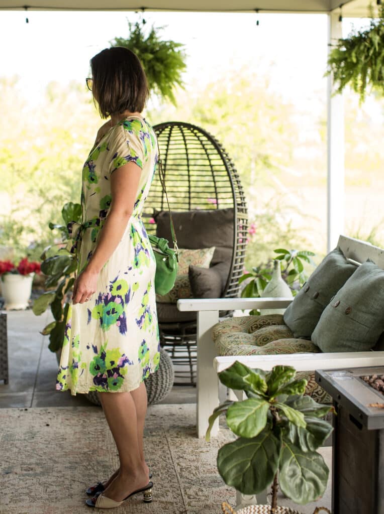 Lindsey wears the Anna Slope Arm Dress in Tuileries Oyster Green on a summer patio