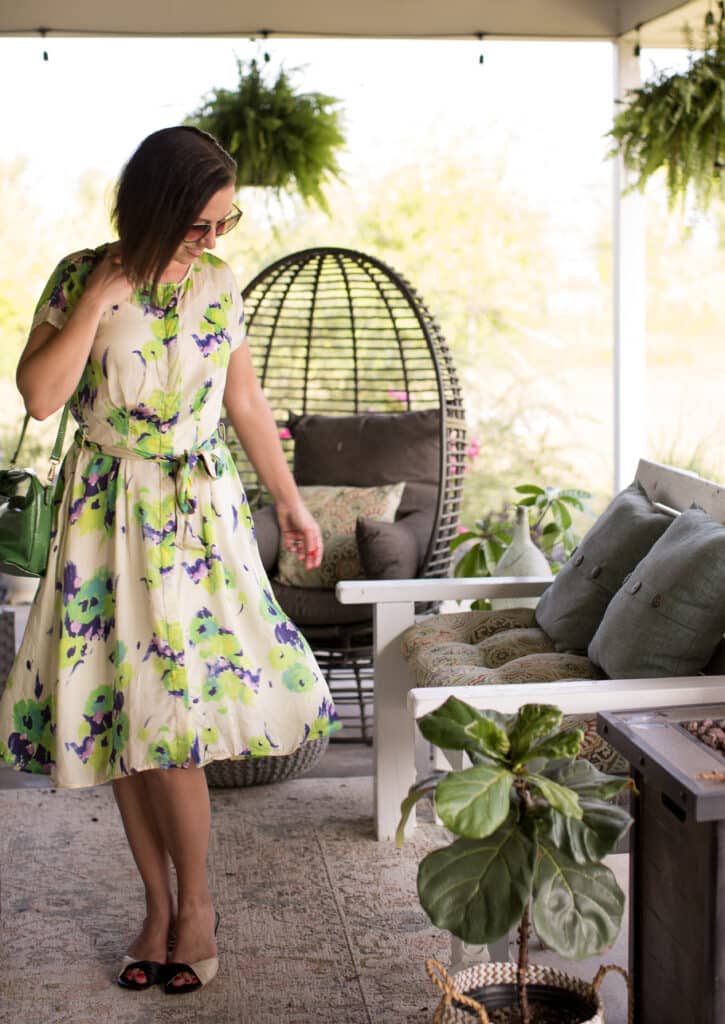 Lindsey wears the Anna Slope Arm Dress in Tuileries Oyster Green on a summer patio