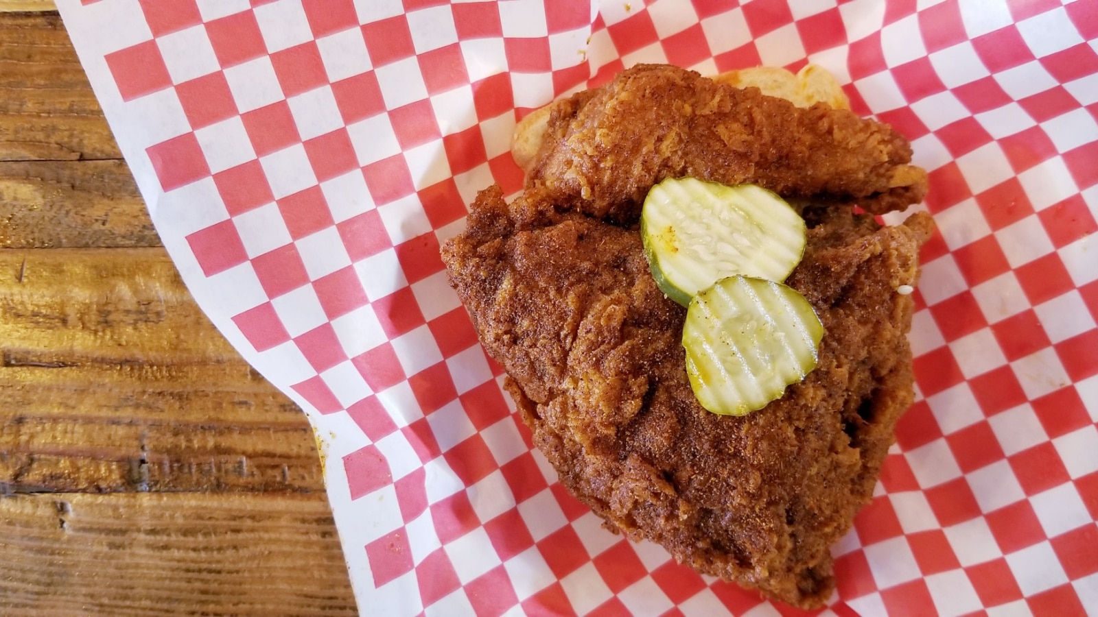 Top View Of Fried Chicken with Wooden Table Top Surface. Famous Nashville Hot Chicken with Pickled Cucumber. Crispy Fried Chicken Breast with Skin On.