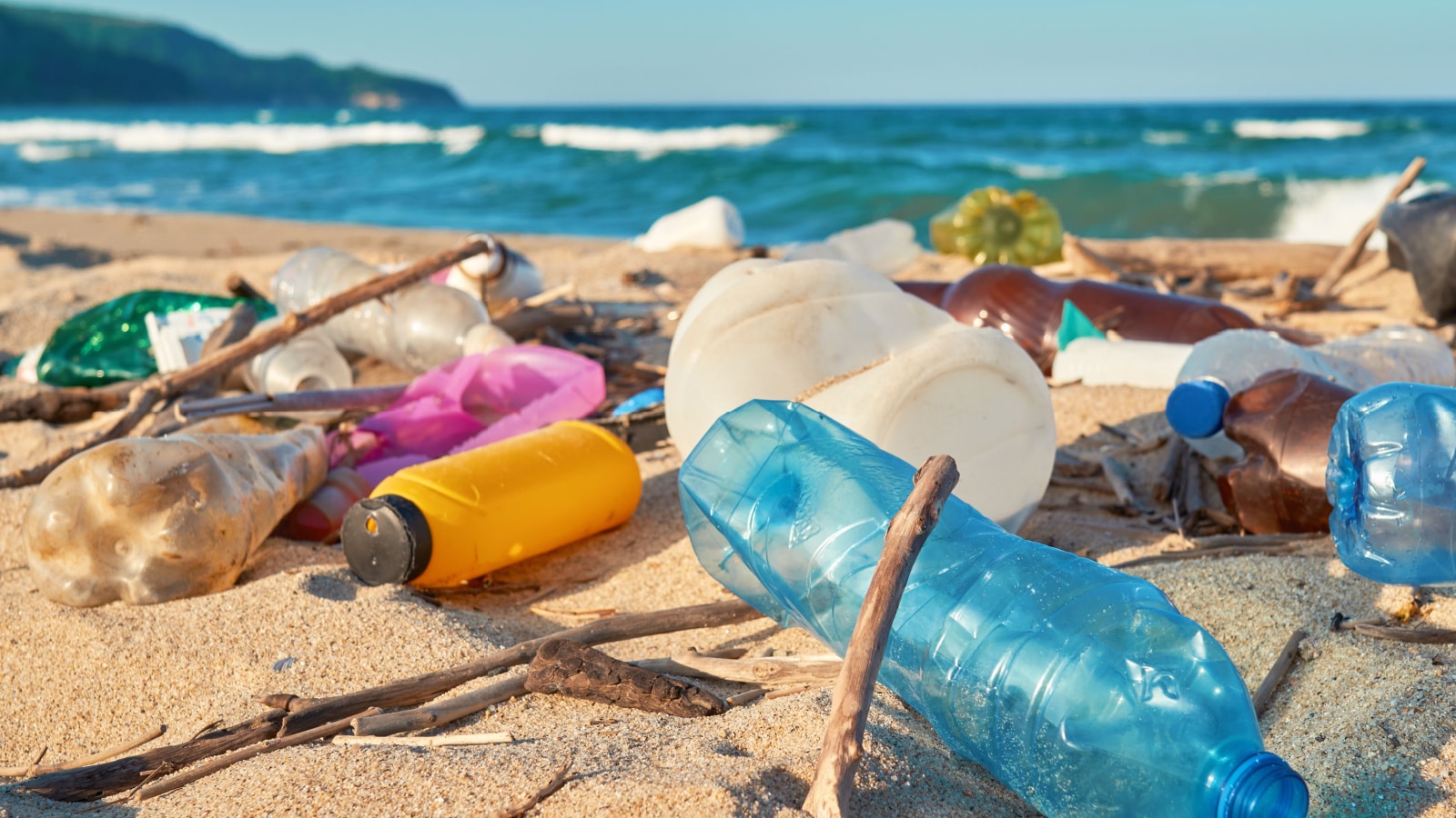 Spilled garbage on beach of big city. Empty used dirty plastic bottles. Dirty sea sandy shore the Black Sea. Environmental pollution. Ecological problem. Bokeh moving waves in the background