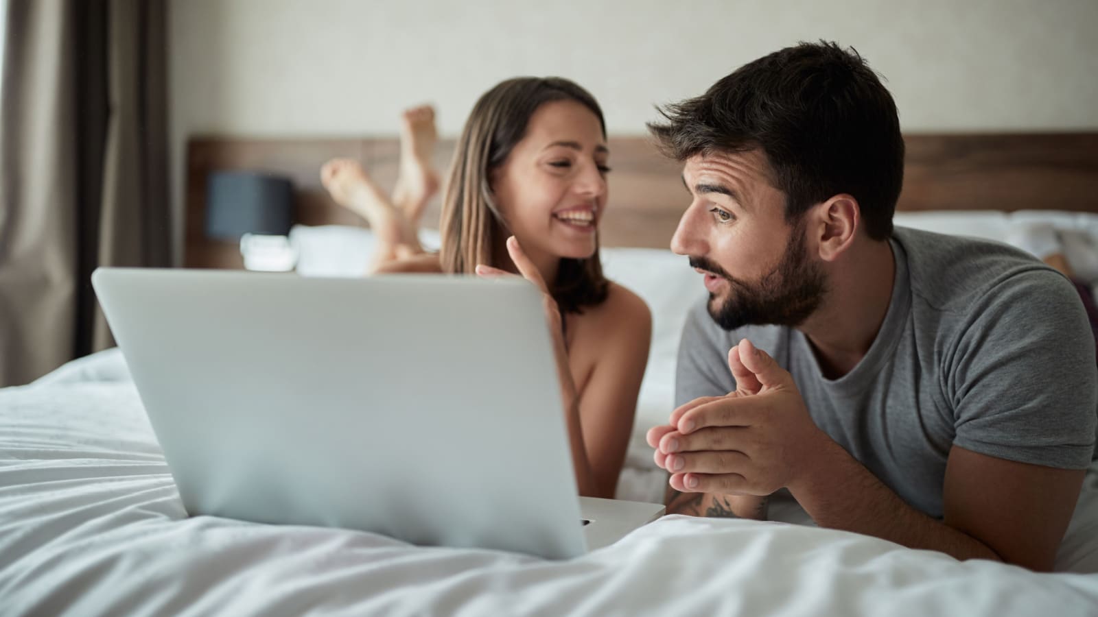 Happy young couple is having fun in bed together