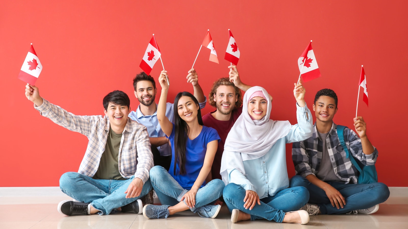 Group of students with Canadian flags sitting near color wall