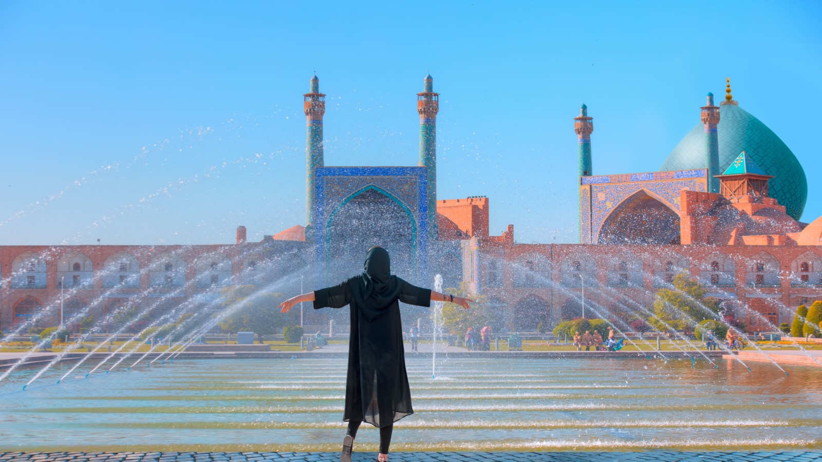 Beautiful Iranian girl wearing abaya with arms up happy - Shah (Imam) Mosque (Jameh Abbasi Mosque), Imam mosque in Naghsh-i Jahan Square - Isfahan, Iran,