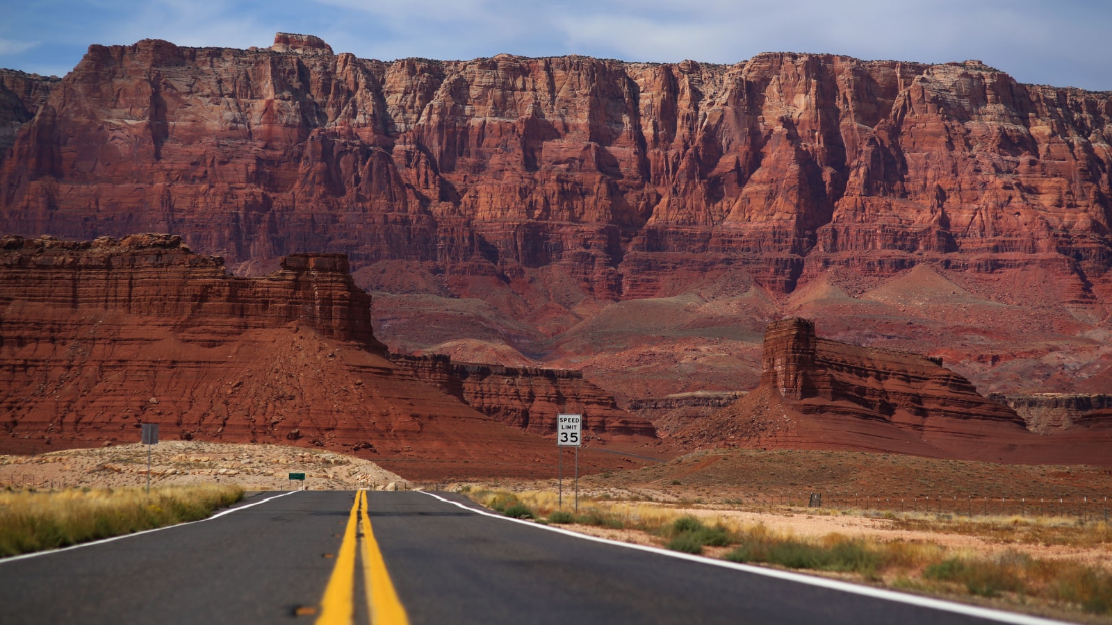Road with the yellow divider lines leading to red rocks formations in Arizona
