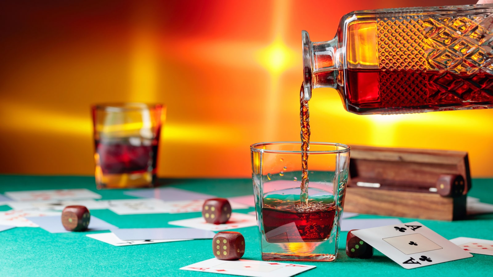Casino table with cards and dice . Whisky is poured into a glass from a decanter . Concept of gambling in casino.
