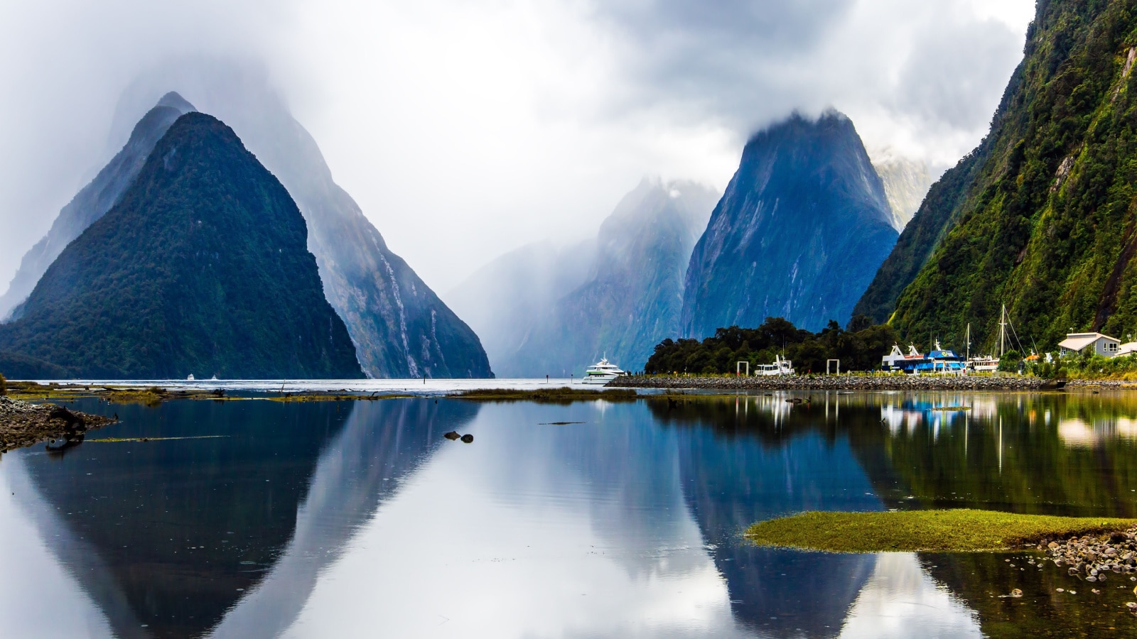 Land of hobbits - New Zealand. Port of tourist and pleasure ships, yachts and boats. Storm clouds cover the sky over the ocean fjord Milford Sound. Concept of exotic, photographic tourism
